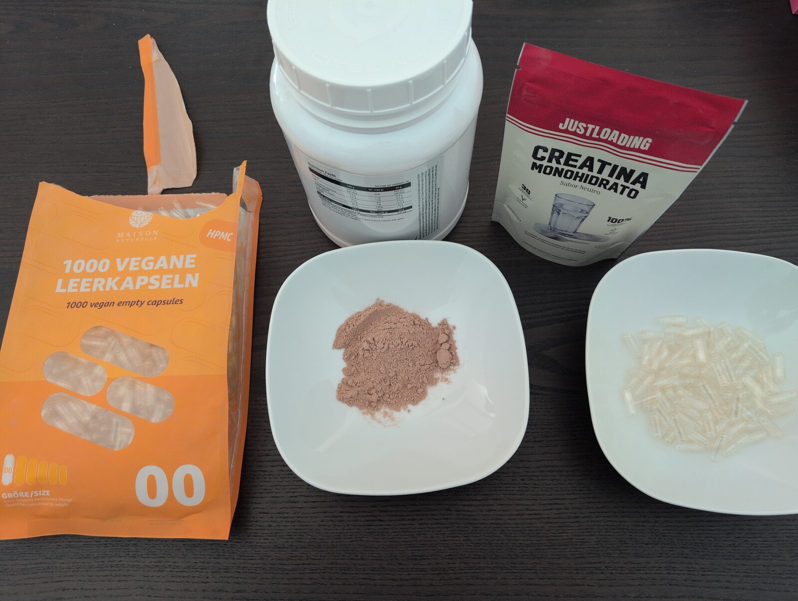 Protein powder on one bowl, capsules of size 00 on another