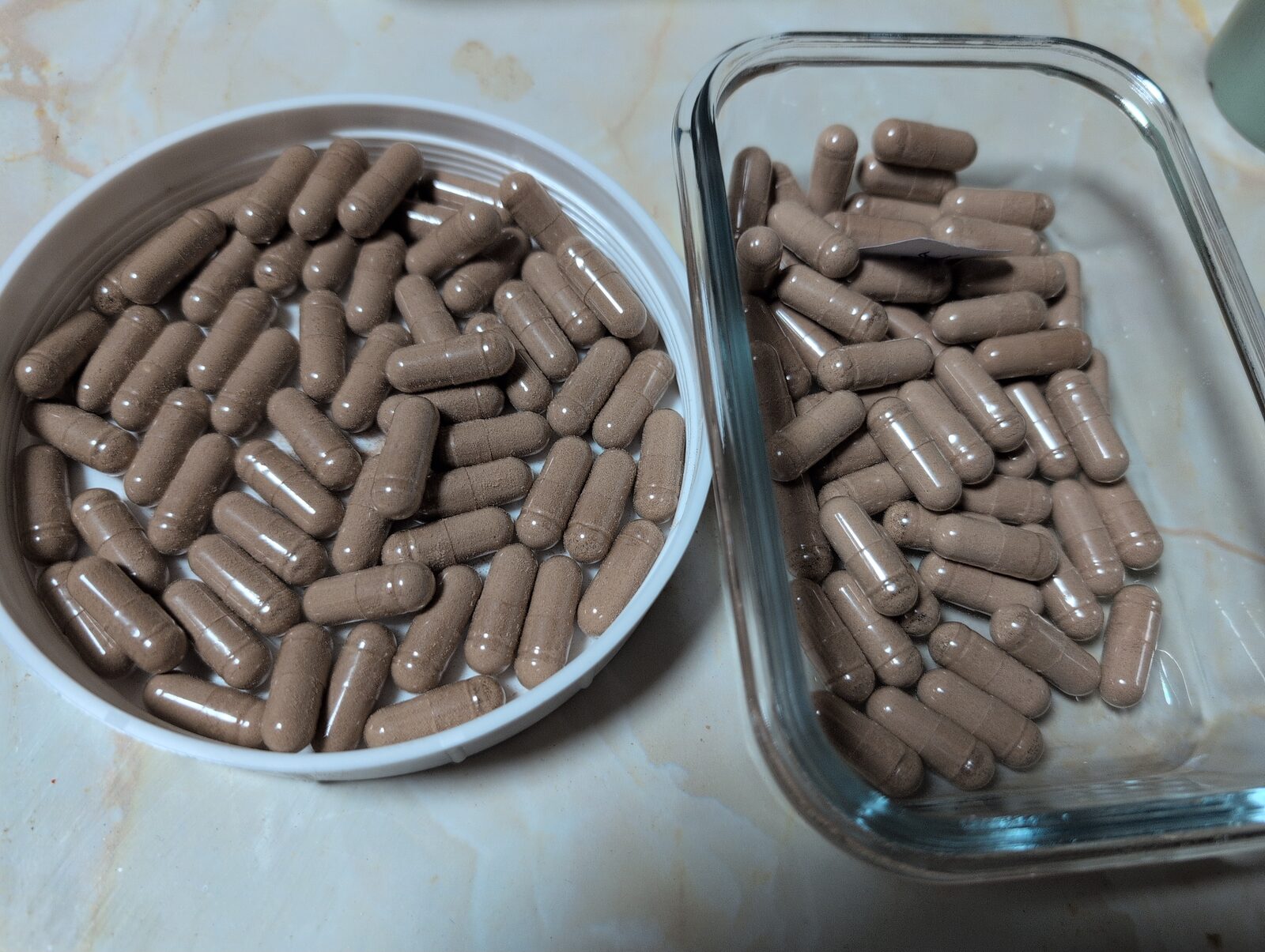 Two containers filled with homemade capsules, one has a piece of paper